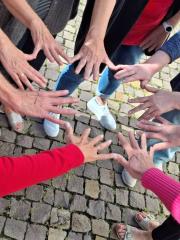 Viele Hände werden im Kreis nach innen gestreckt.